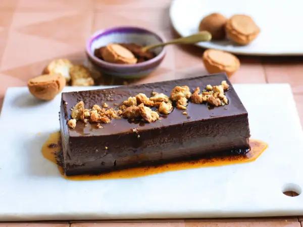 Bonet piemontese al cioccolato, lucido e cremoso, guarnito con briciole croccanti e salsa caramello.
