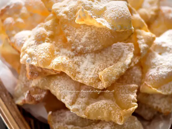 Chiacchiere croccanti, una deliziosa chiacchiere ricetta della nonna, cosparse di zucchero a velo.